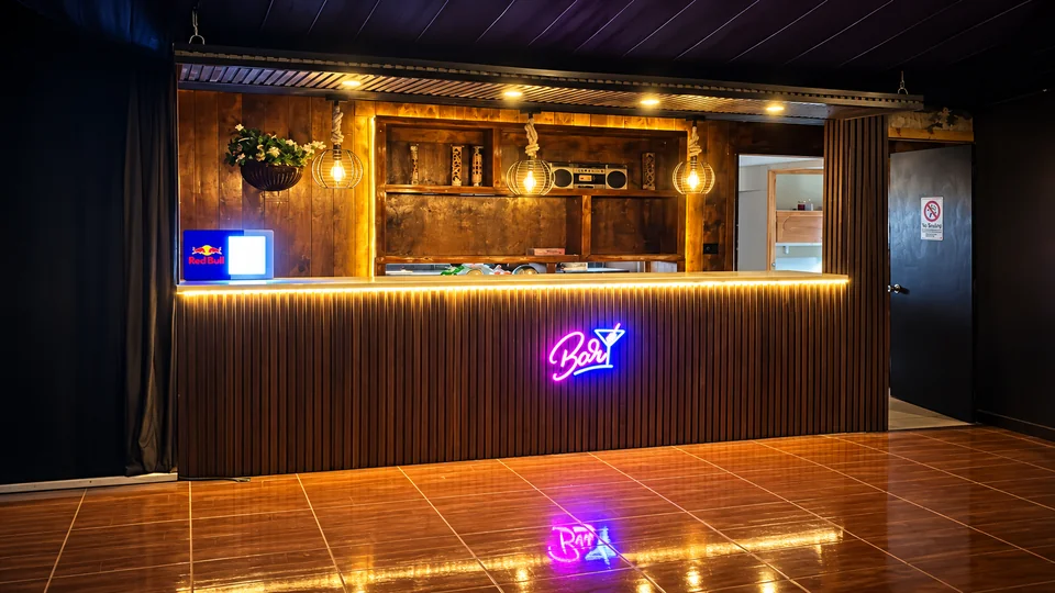 Bar interior de madera con iluminación cálida y letrero luminoso